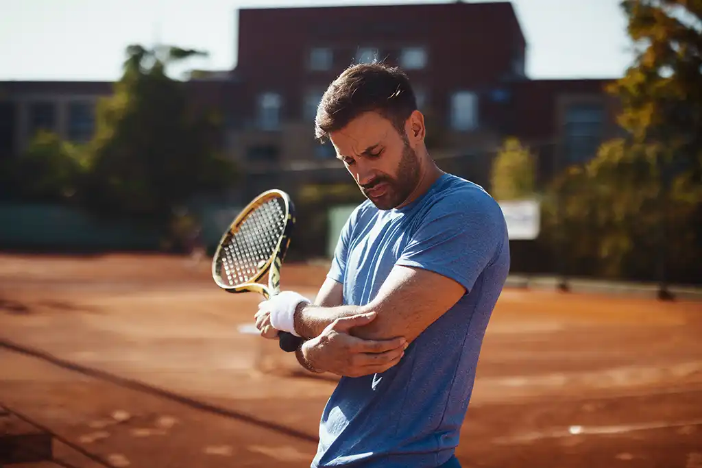 man with elbow pain playing tennis