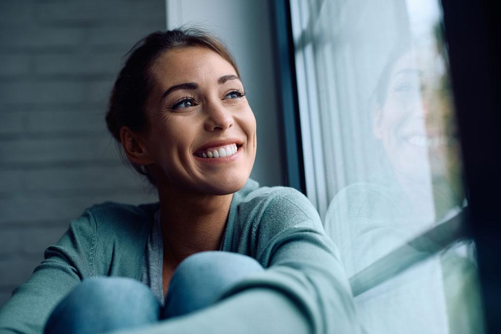 woman smiling while looking out of window